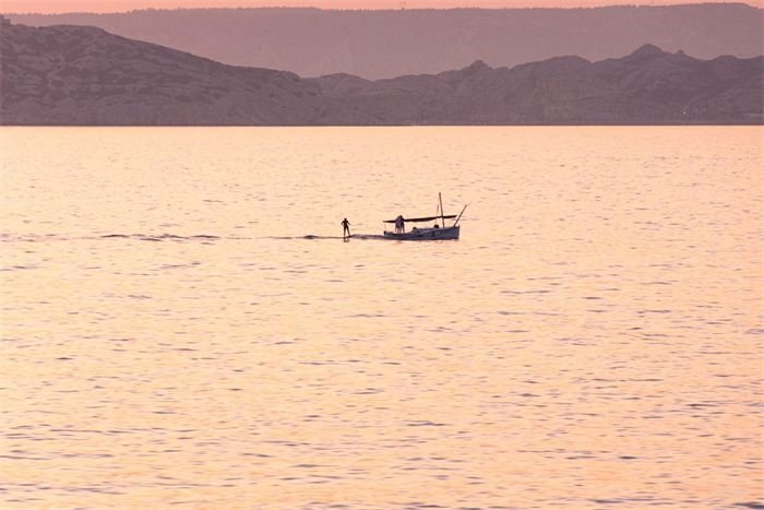 Barque sur une mer rosée au soleil couchant